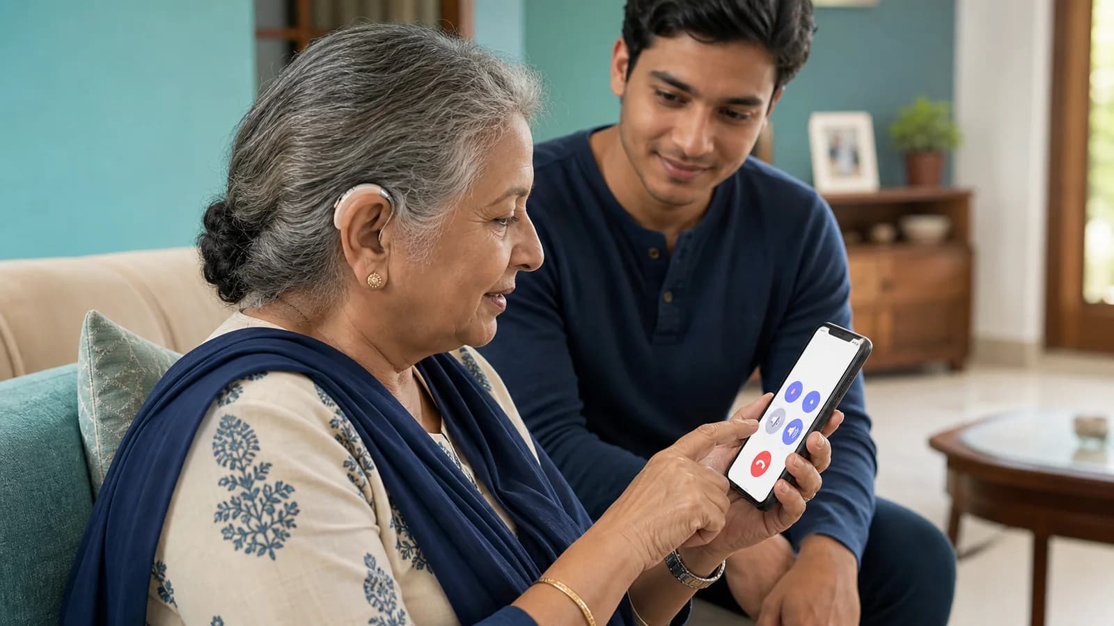 An older Indian woman with a hearing aid using accessible phone controls with family support